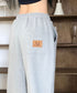 MUCENT(ムセント)/ユニセックス ワイド ルーズ ロゴ ジョガー スウェットパンツ/LASH METAL LOGO JOGGER SWEAT WIDE PANTS UNISEX | AT2252030 | グレー